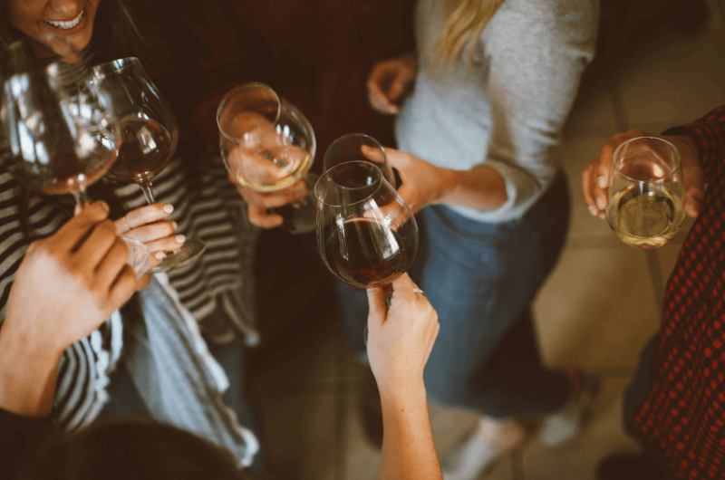 přátelelé si v krhu přiťukávají skleničkami s vínem