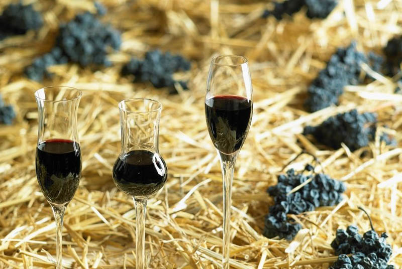 Winogrona suszone na słomie oraz kieliszki z winem
